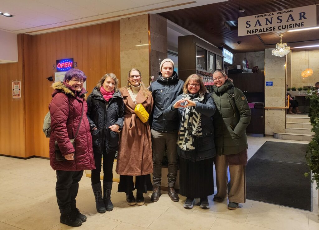 Hallituslaiset seisovat talvitakeissaan ravintola Sansarin edessä kameralle hymyillen. Seisomajärjestys: Mara, Salla, Silja, Aki, Satu joka näyttää käsillään sydämen muotoa ja Petra.